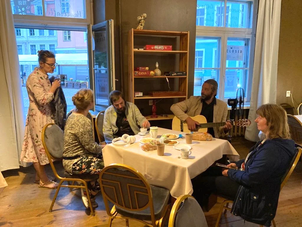A table at Miracle Fellowship with people, one of whom is playing a guitar